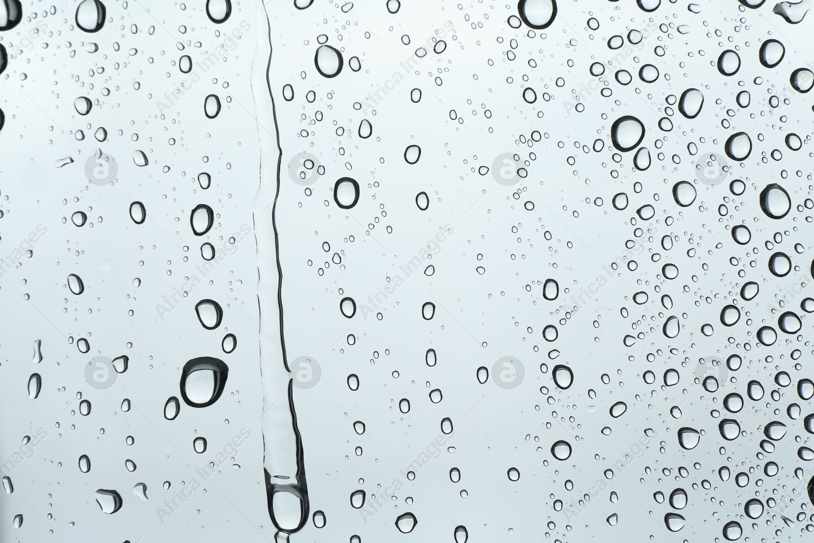 Photo of Many water drops on light glass surface, closeup