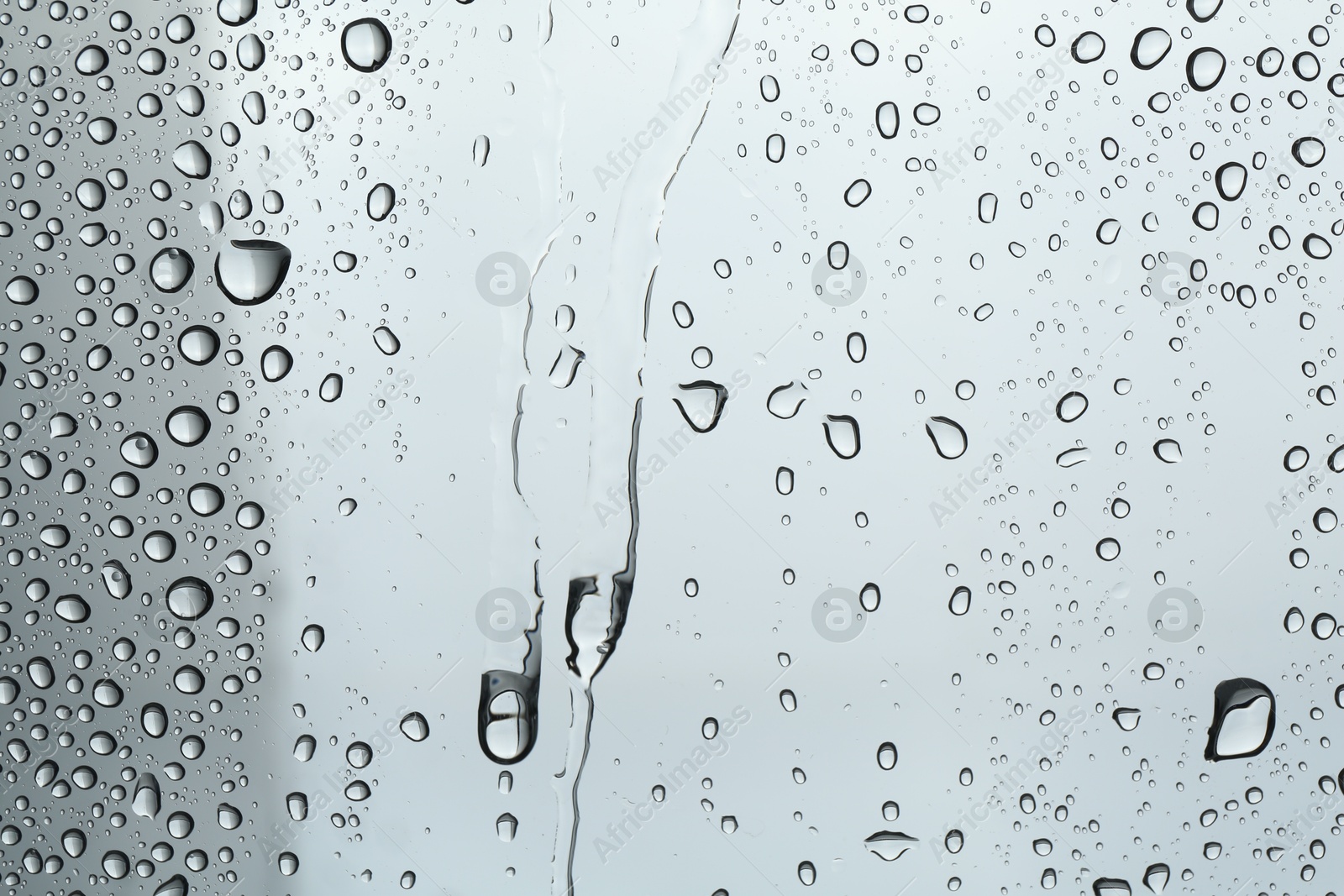 Photo of Many water drops on light glass surface, closeup