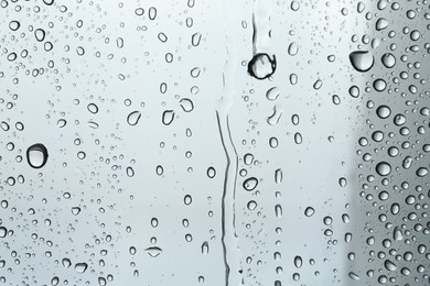 Many water drops on light glass surface, closeup