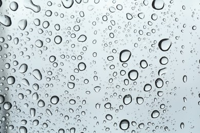 Photo of Many water drops on light glass surface, closeup