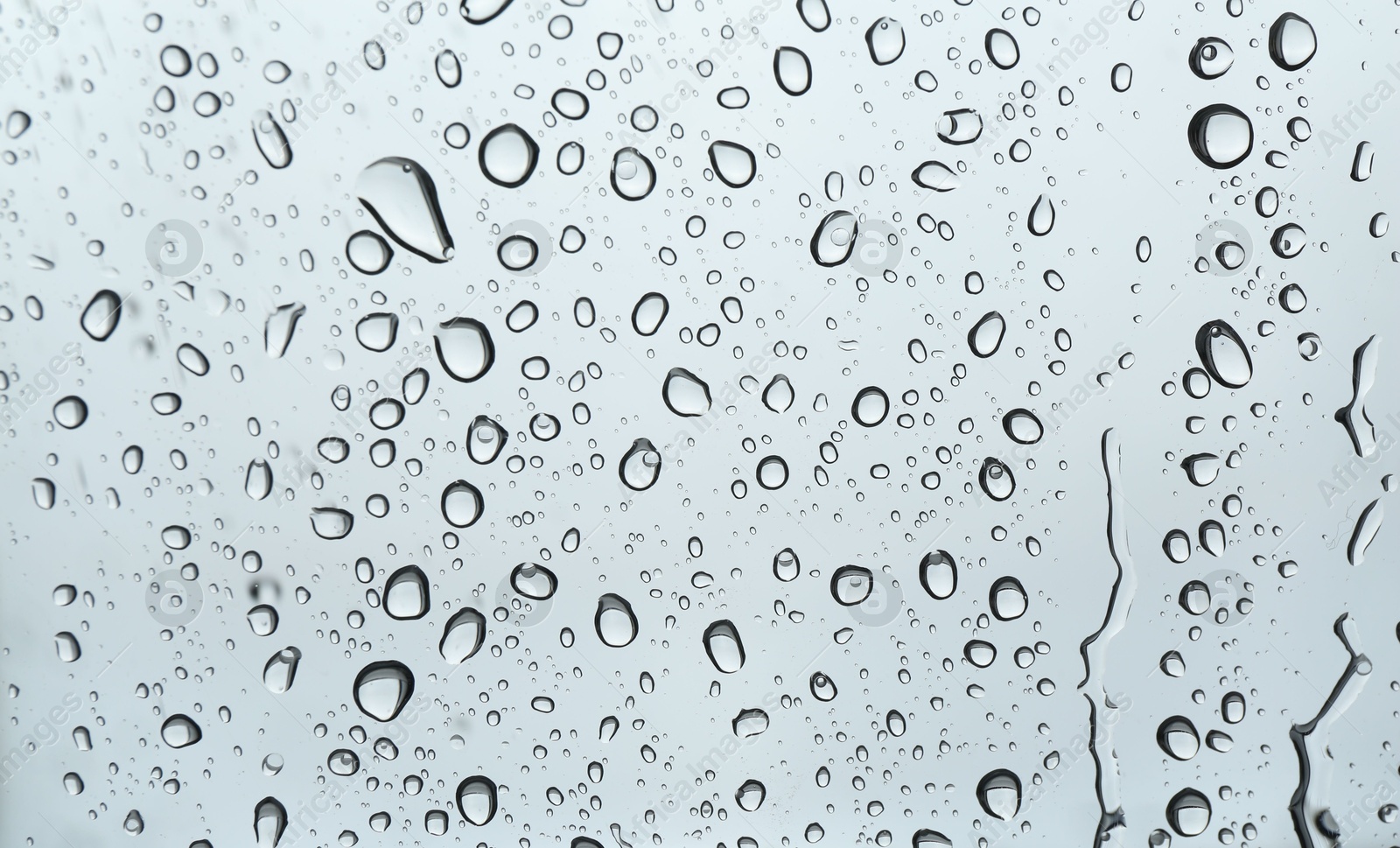 Photo of Many water drops on light glass surface, closeup