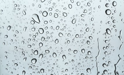 Photo of Many water drops on light glass surface, closeup