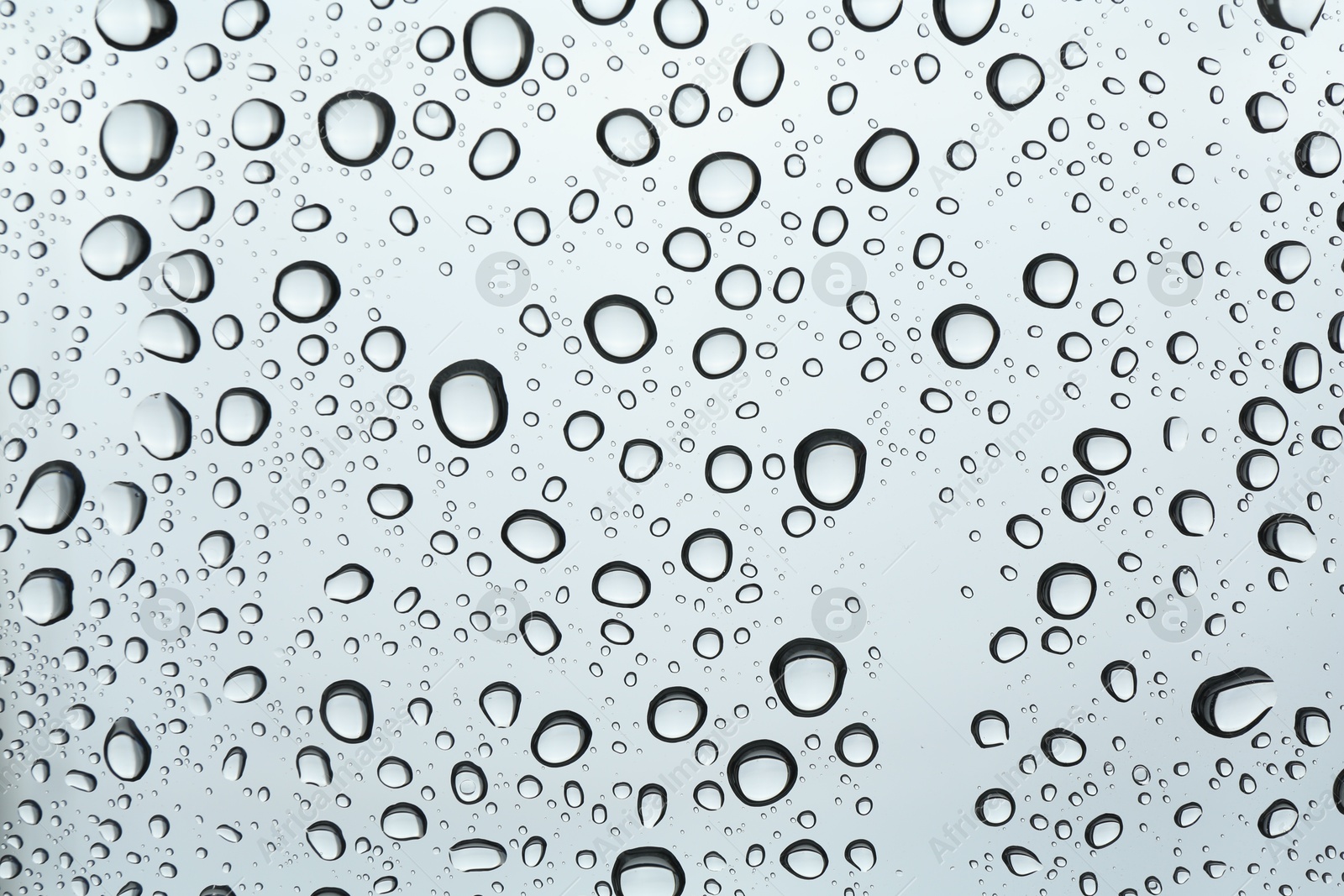 Photo of Many water drops on light glass surface, closeup