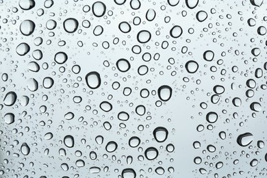 Many water drops on light glass surface, closeup