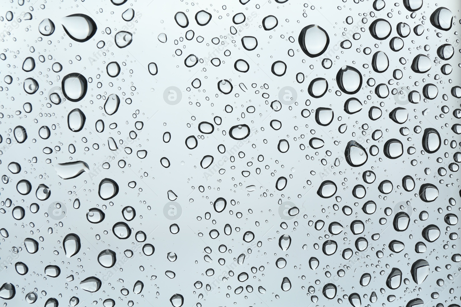 Photo of Many water drops on light glass surface, closeup