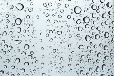 Photo of Many water drops on light glass surface, closeup