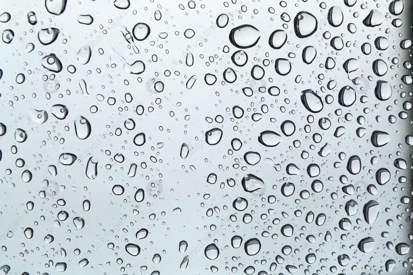 Photo of Many water drops on light glass surface, closeup