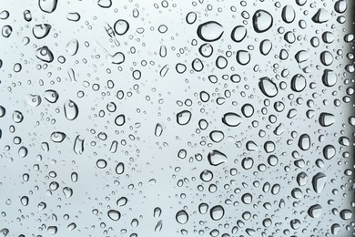 Photo of Many water drops on light glass surface, closeup