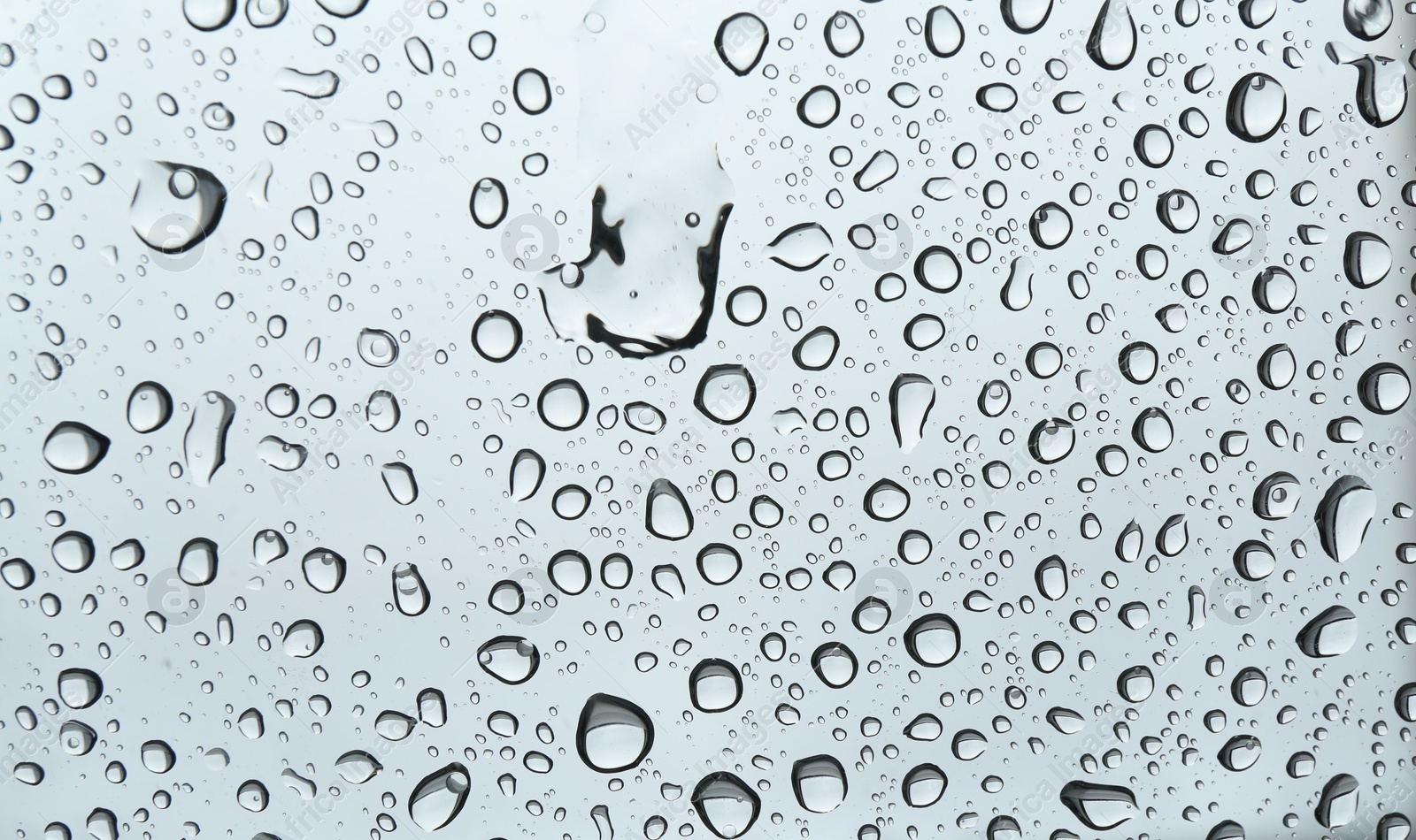 Photo of Many water drops on light glass surface, closeup