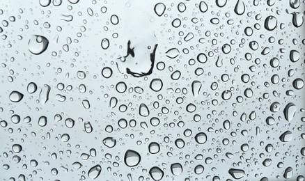 Many water drops on light glass surface, closeup