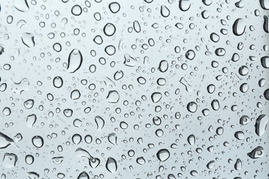 Photo of Many water drops on light glass surface, closeup