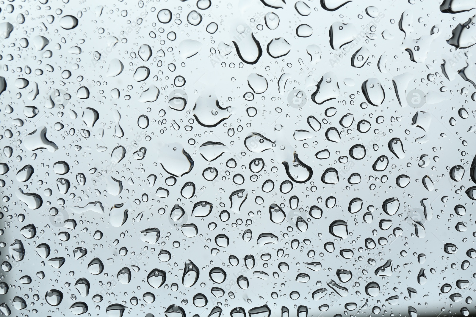 Photo of Many water drops on light glass surface, closeup