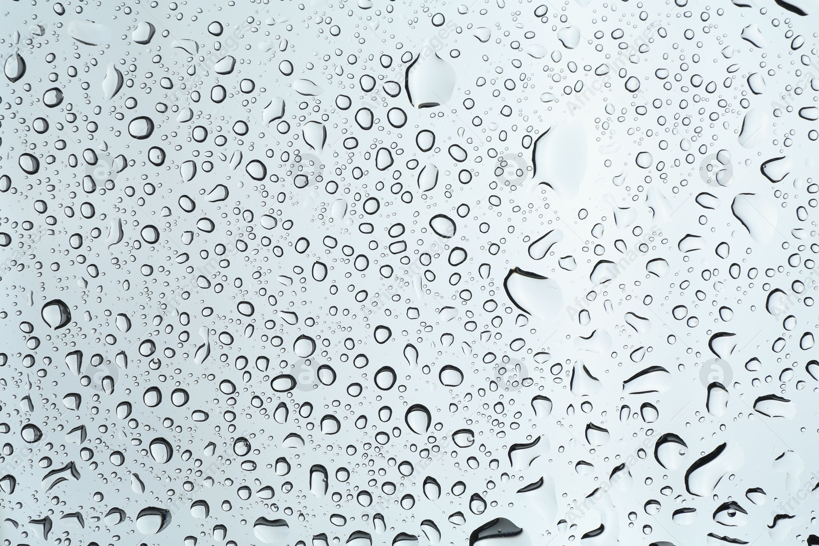 Photo of Many water drops on light glass surface, closeup