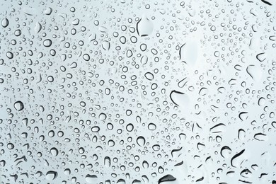 Photo of Many water drops on light glass surface, closeup