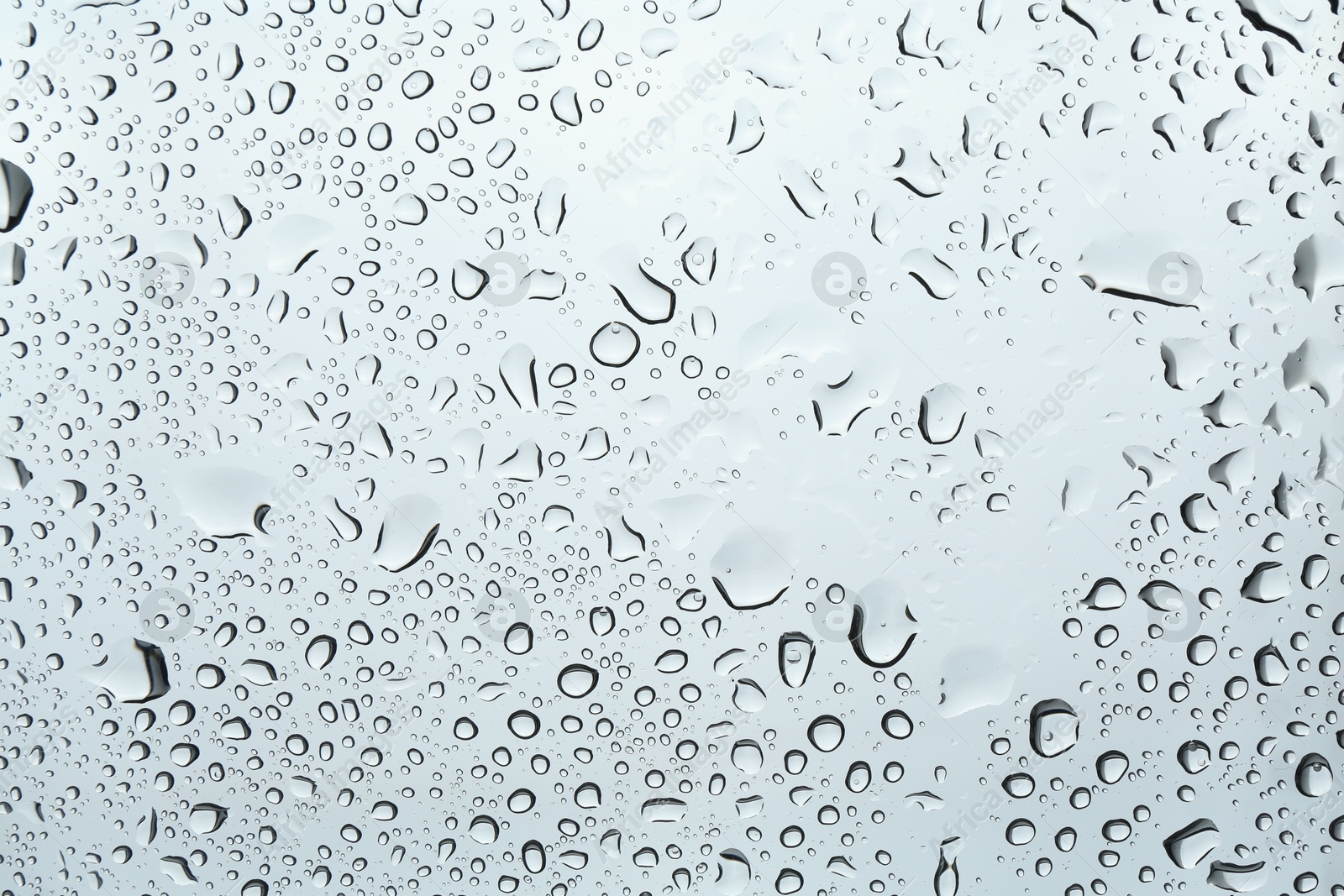 Photo of Many water drops on light glass surface, closeup