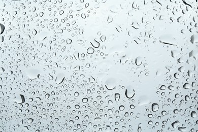 Many water drops on light glass surface, closeup