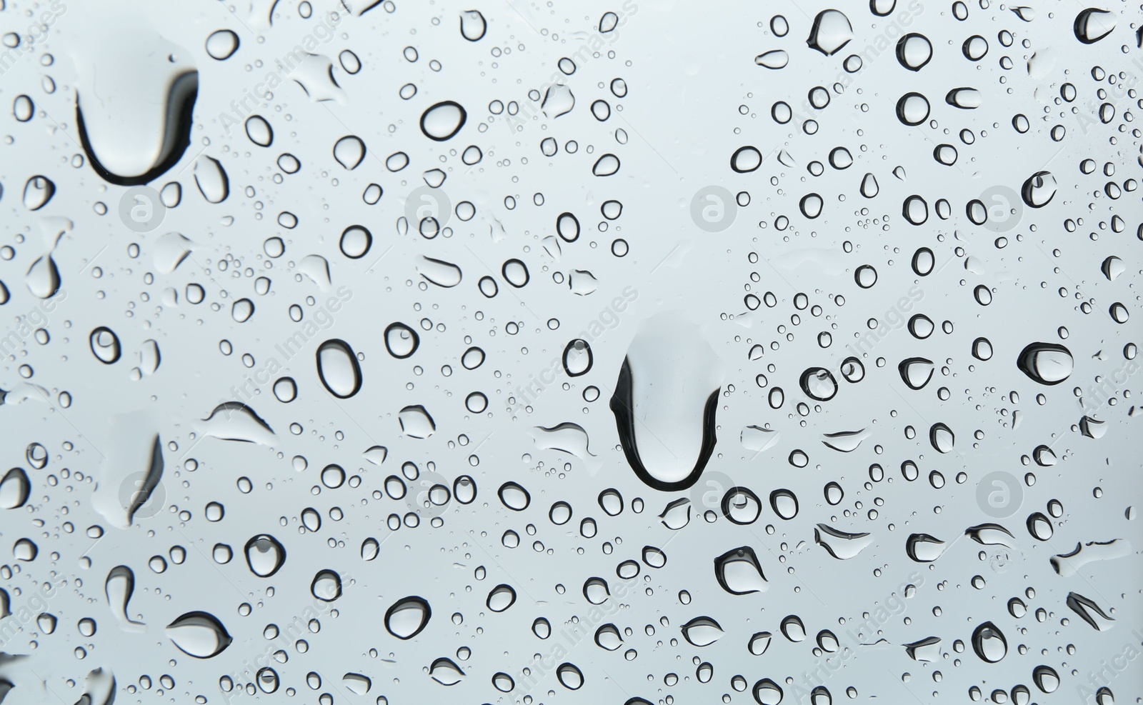 Photo of Many water drops on light glass surface, closeup