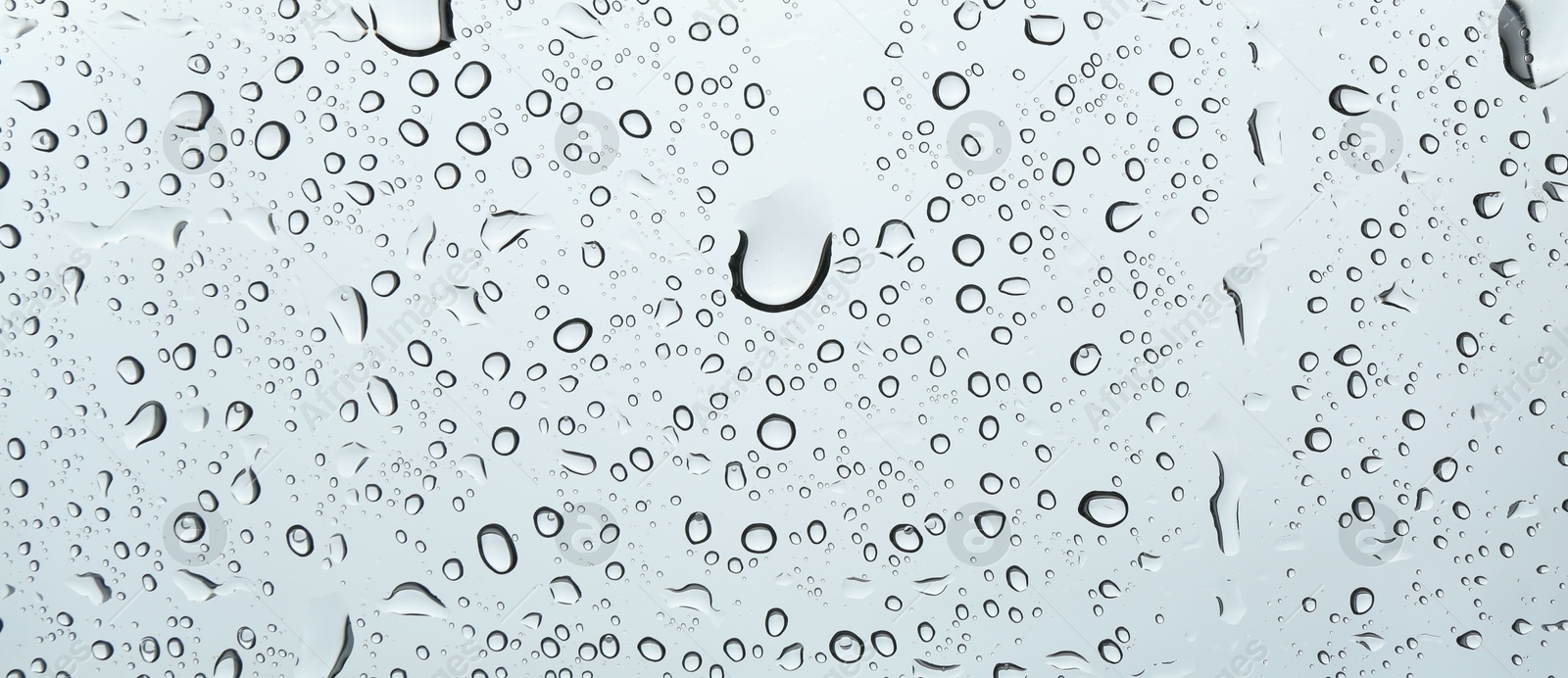 Photo of Many water drops on light glass surface, closeup