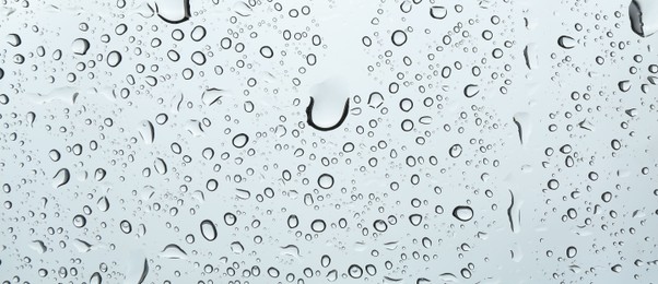 Photo of Many water drops on light glass surface, closeup