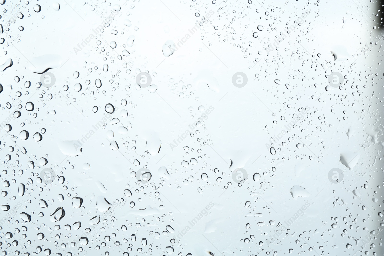 Photo of Many water drops on light glass surface, closeup