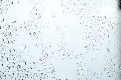 Photo of Many water drops on light glass surface, closeup