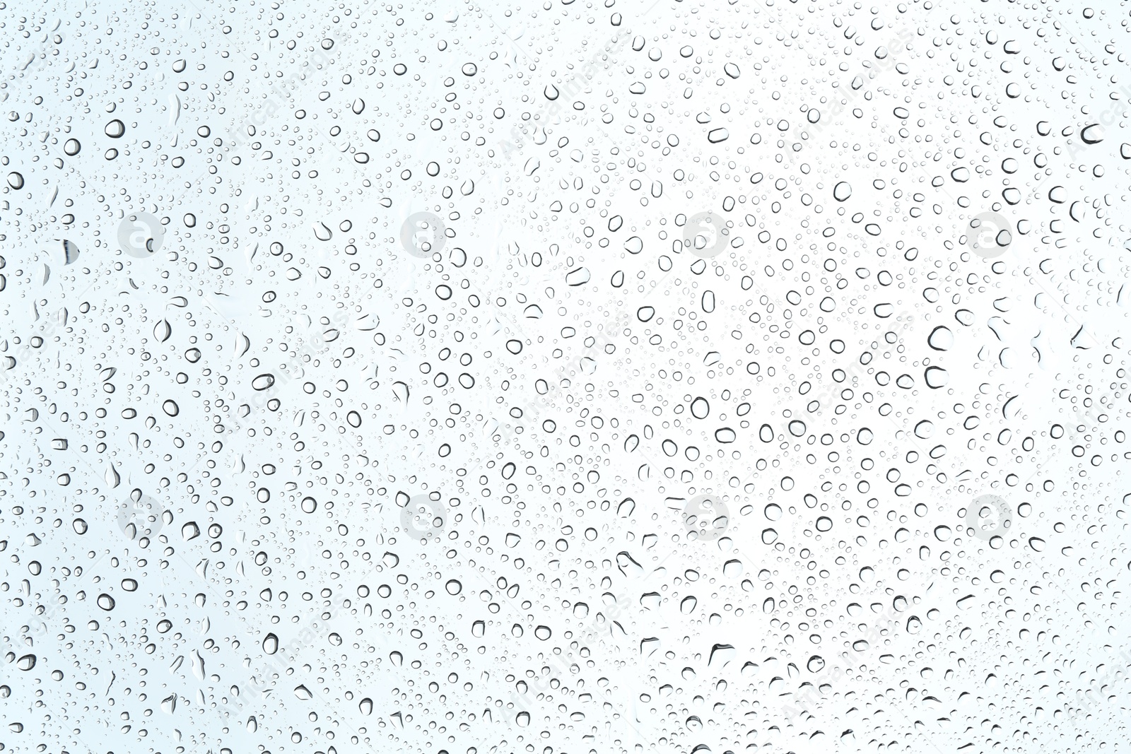 Photo of Many water drops on light glass surface, closeup