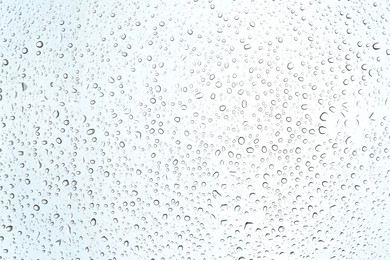 Photo of Many water drops on light glass surface, closeup