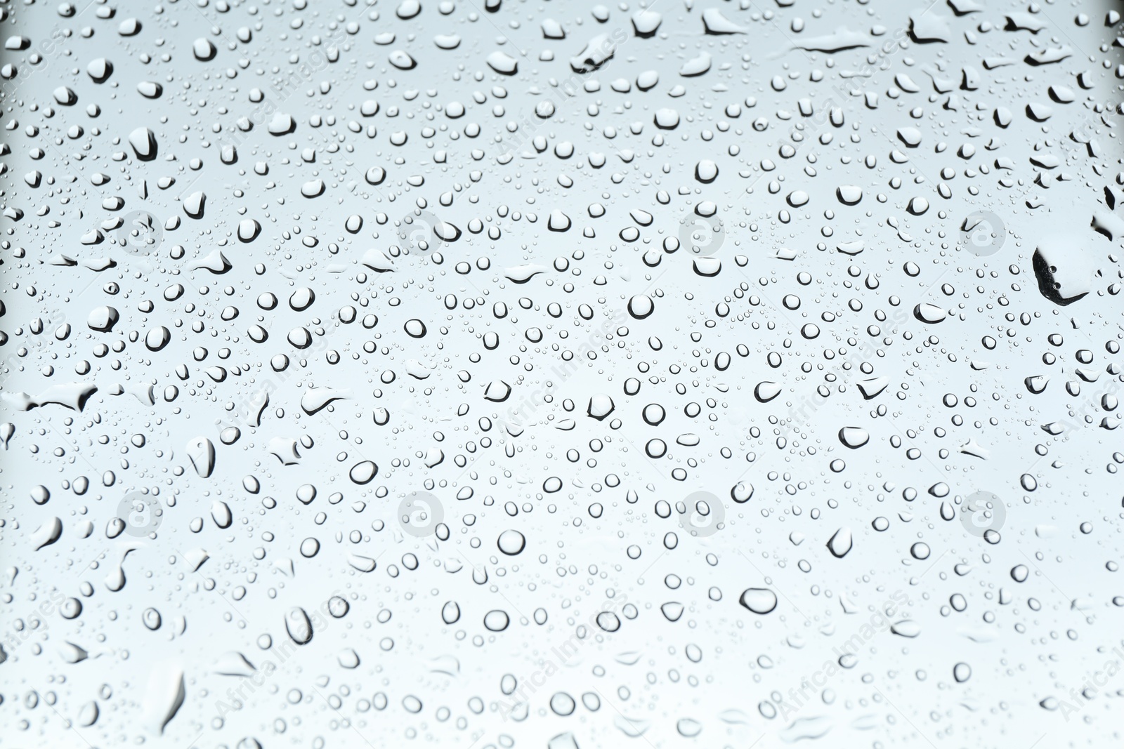 Photo of Many water drops on light glass surface, closeup