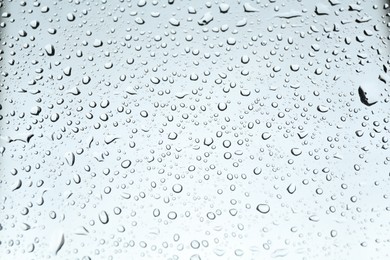 Photo of Many water drops on light glass surface, closeup