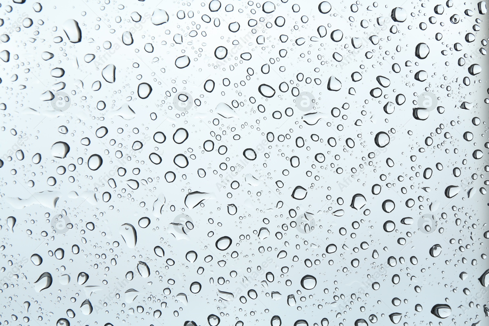 Photo of Many water drops on light glass surface, closeup