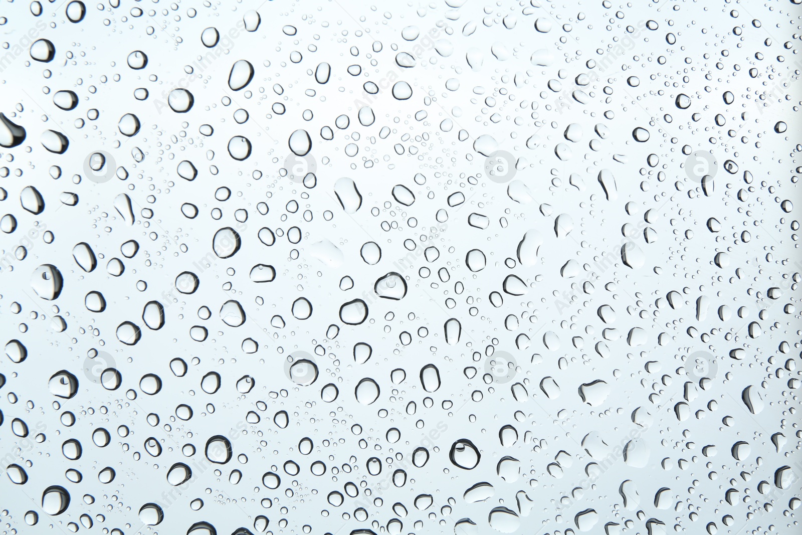 Photo of Many water drops on light glass surface, closeup