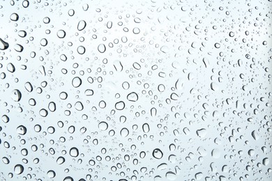 Photo of Many water drops on light glass surface, closeup