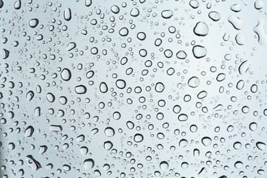 Photo of Many water drops on light glass surface, closeup