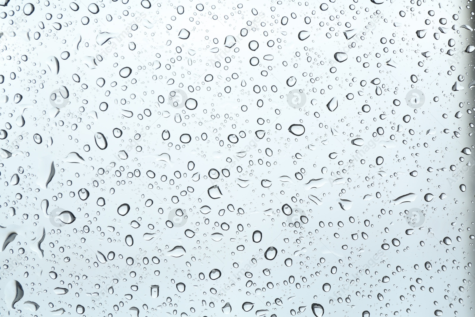 Photo of Many water drops on light glass surface, closeup