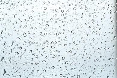 Photo of Many water drops on light glass surface, closeup