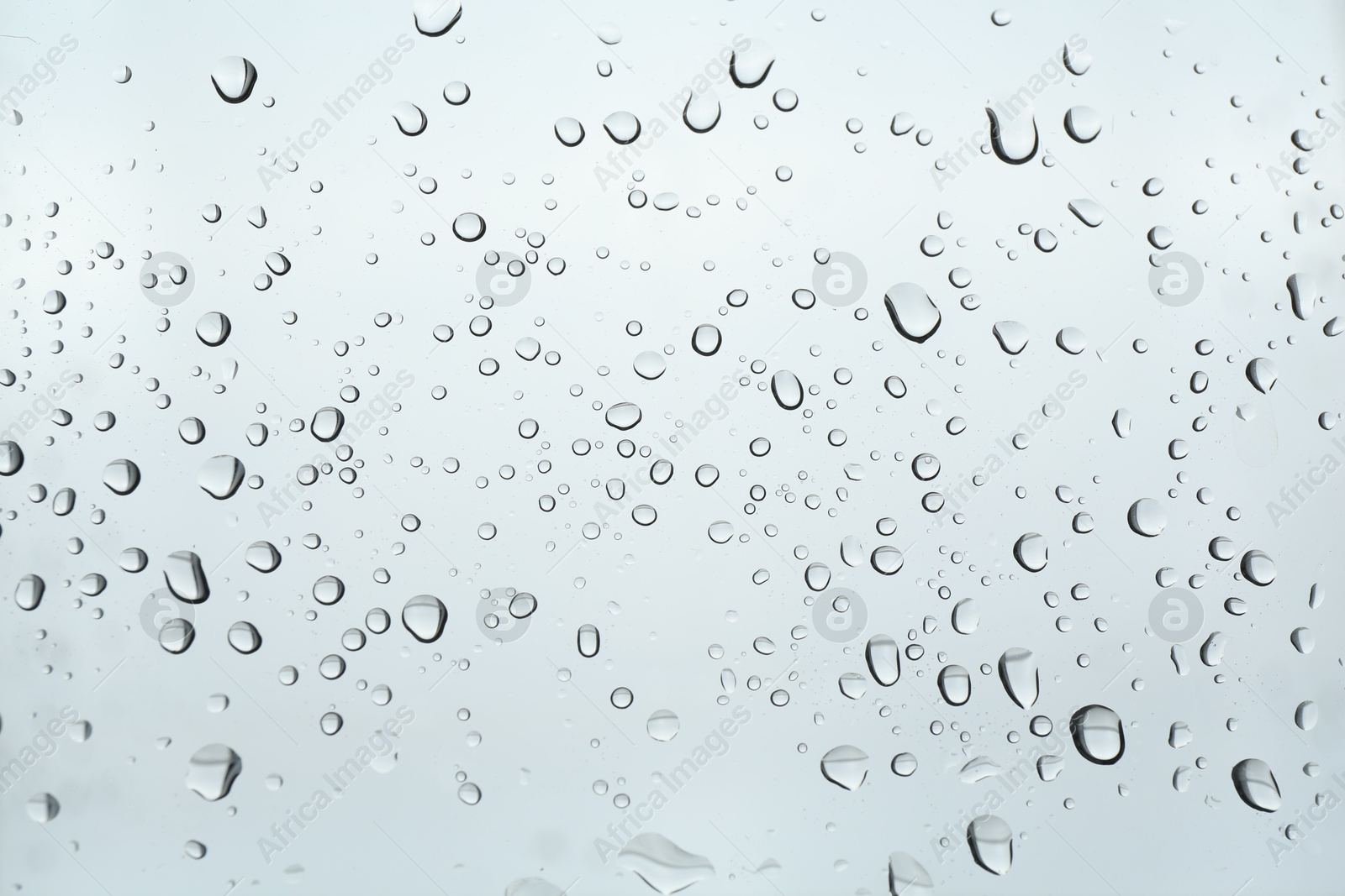 Photo of Many water drops on light glass surface, closeup