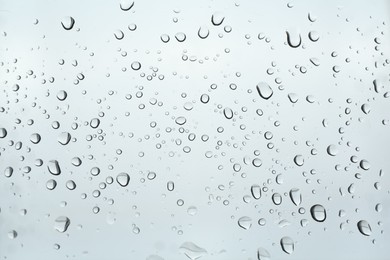 Photo of Many water drops on light glass surface, closeup