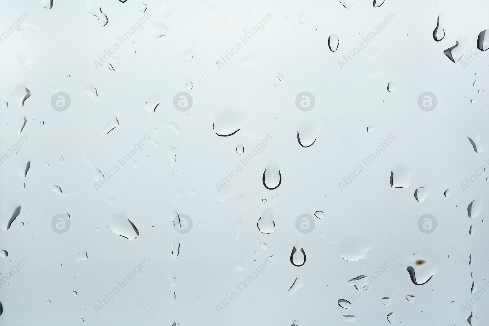 Photo of Many water drops on light glass surface, closeup