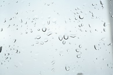 Many water drops on light glass surface, closeup