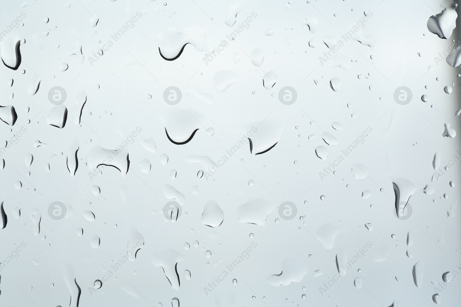 Photo of Many water drops on light glass surface, closeup