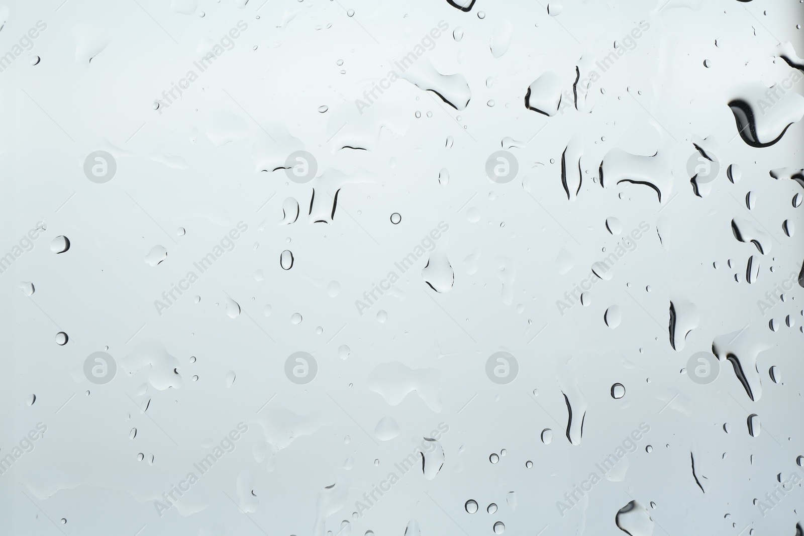 Photo of Many water drops on light glass surface, closeup