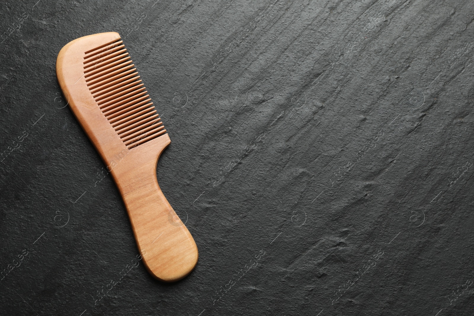 Photo of One wooden hair comb on grey background, top view. Space for text