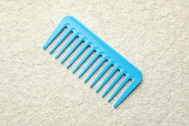 Photo of One light blue plastic comb on beige background, top view