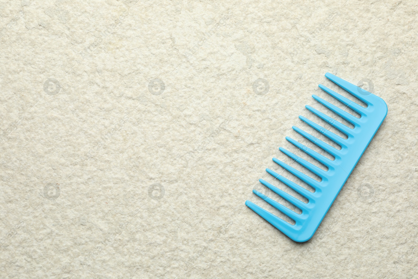 Photo of One light blue plastic comb on beige background, top view. Space for text