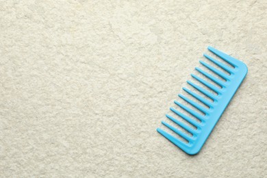 Photo of One light blue plastic comb on beige background, top view. Space for text