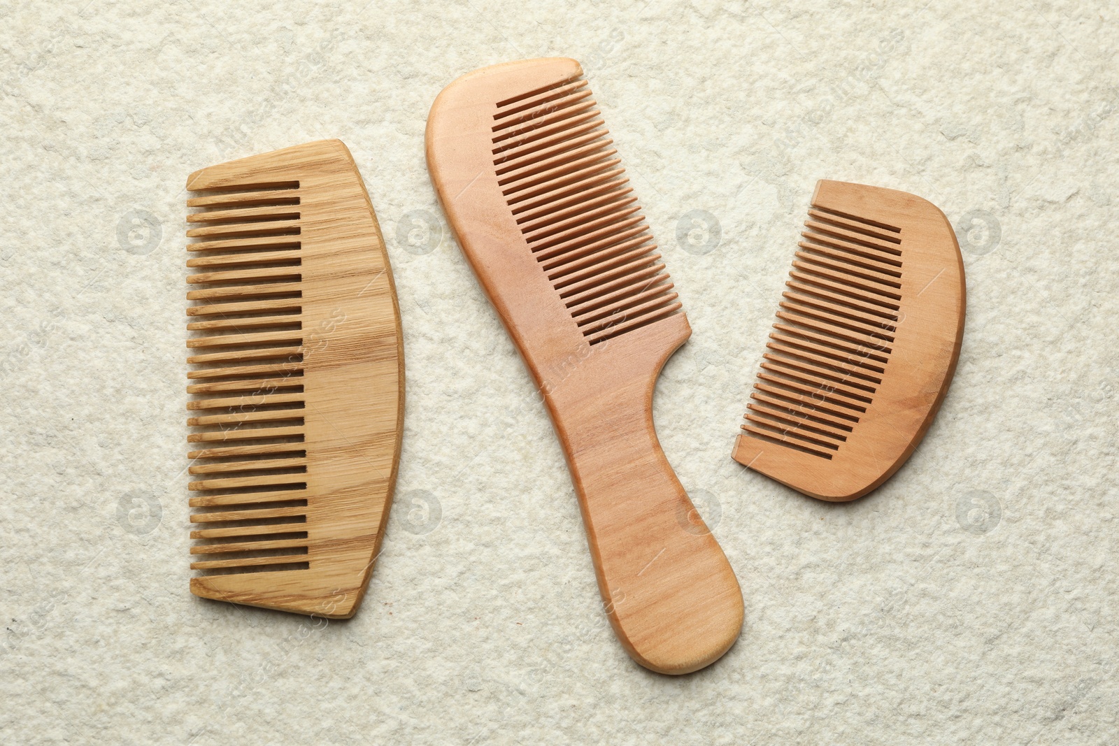 Photo of Different wooden hair combs on beige background, top view