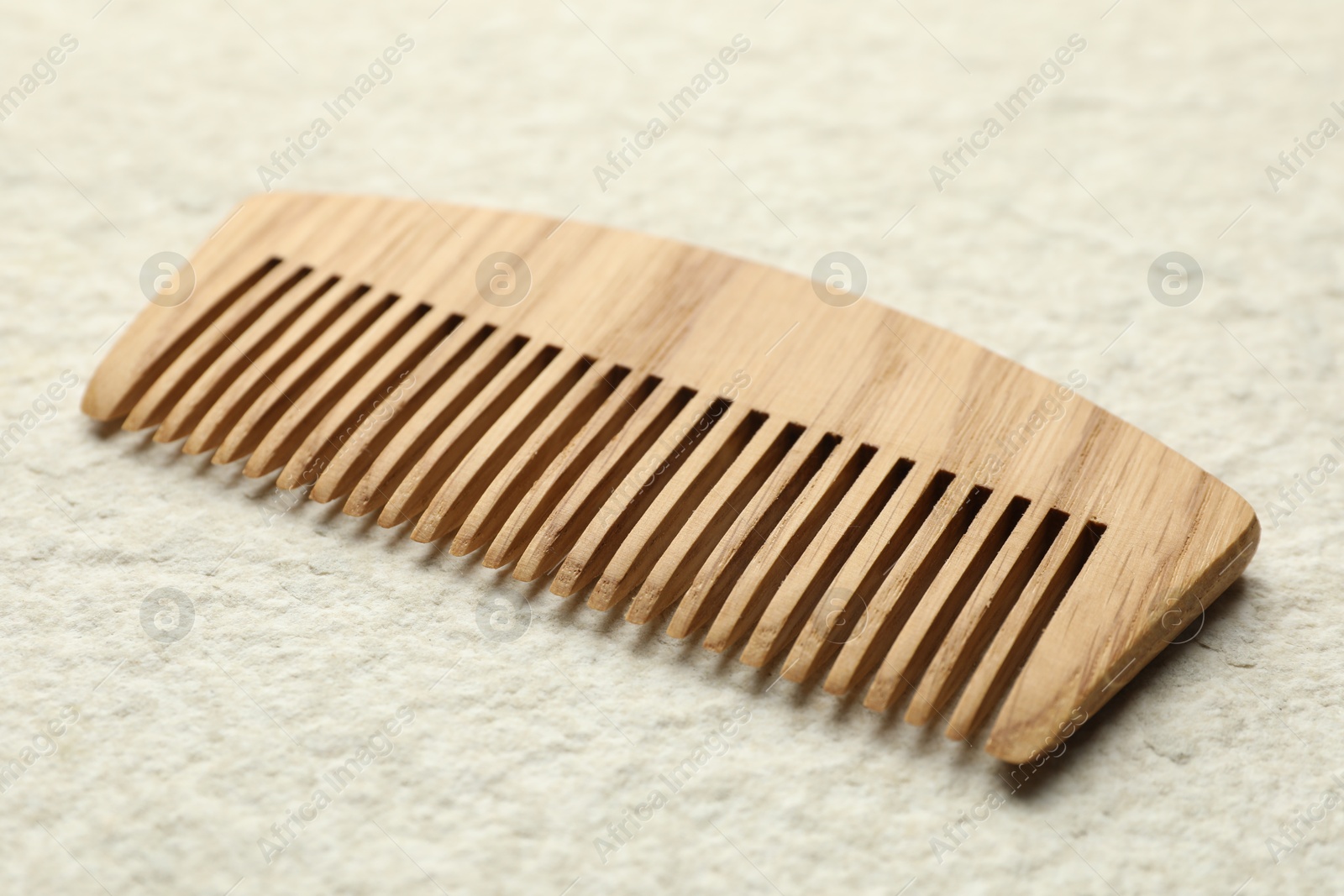 Photo of One wooden hair comb on beige background, closeup