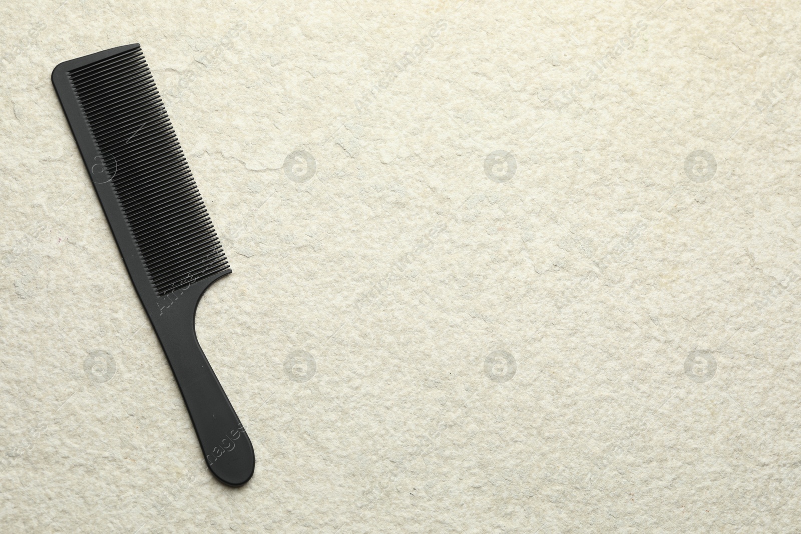 Photo of One black plastic comb on beige background, top view. Space for text