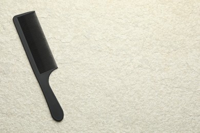 Photo of One black plastic comb on beige background, top view. Space for text