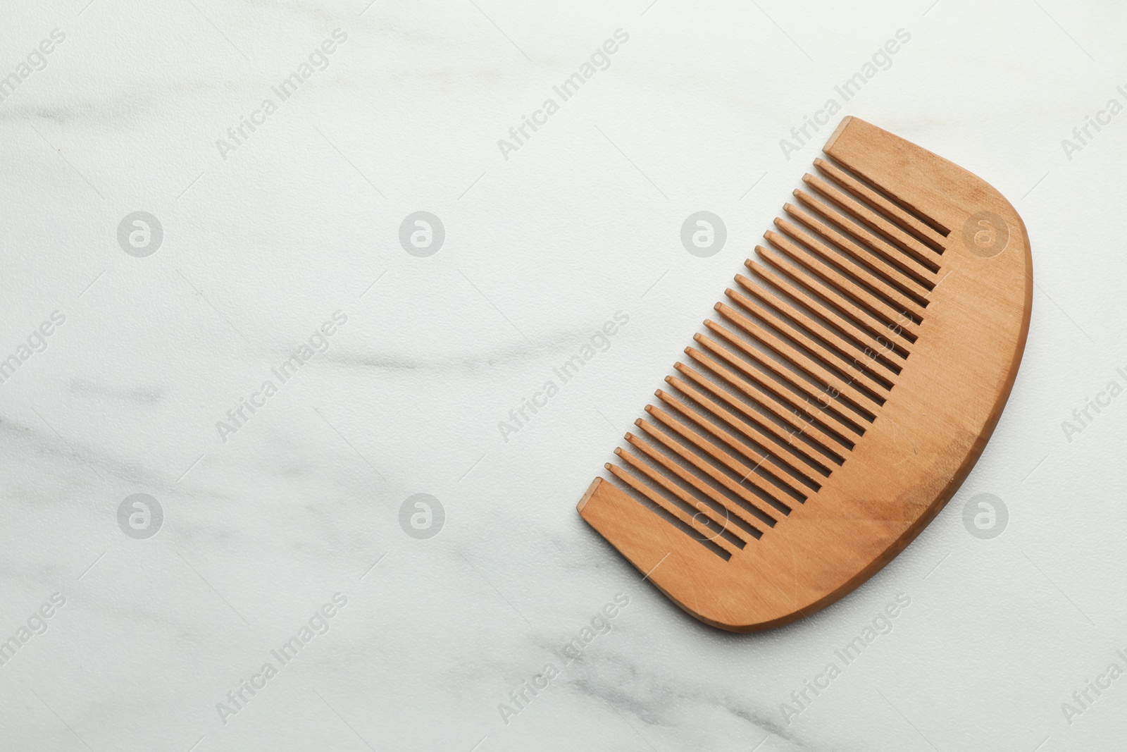 Photo of One wooden hair comb on white marble table, top view. Space for text